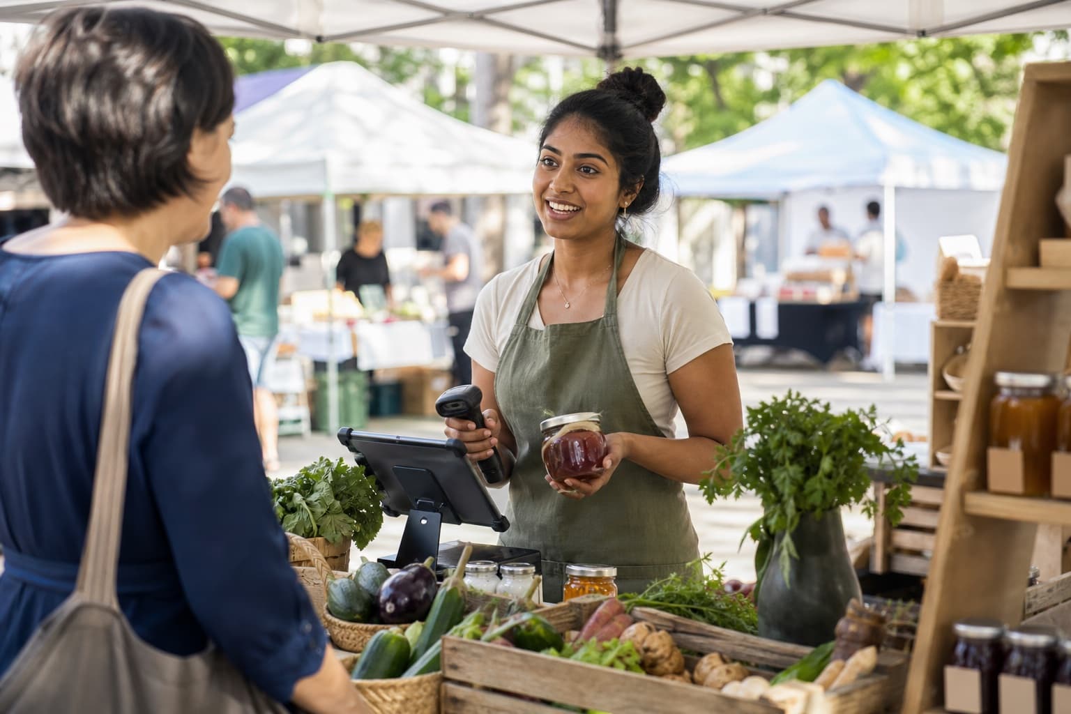 A young market vendor using a tablet checkout at her stall